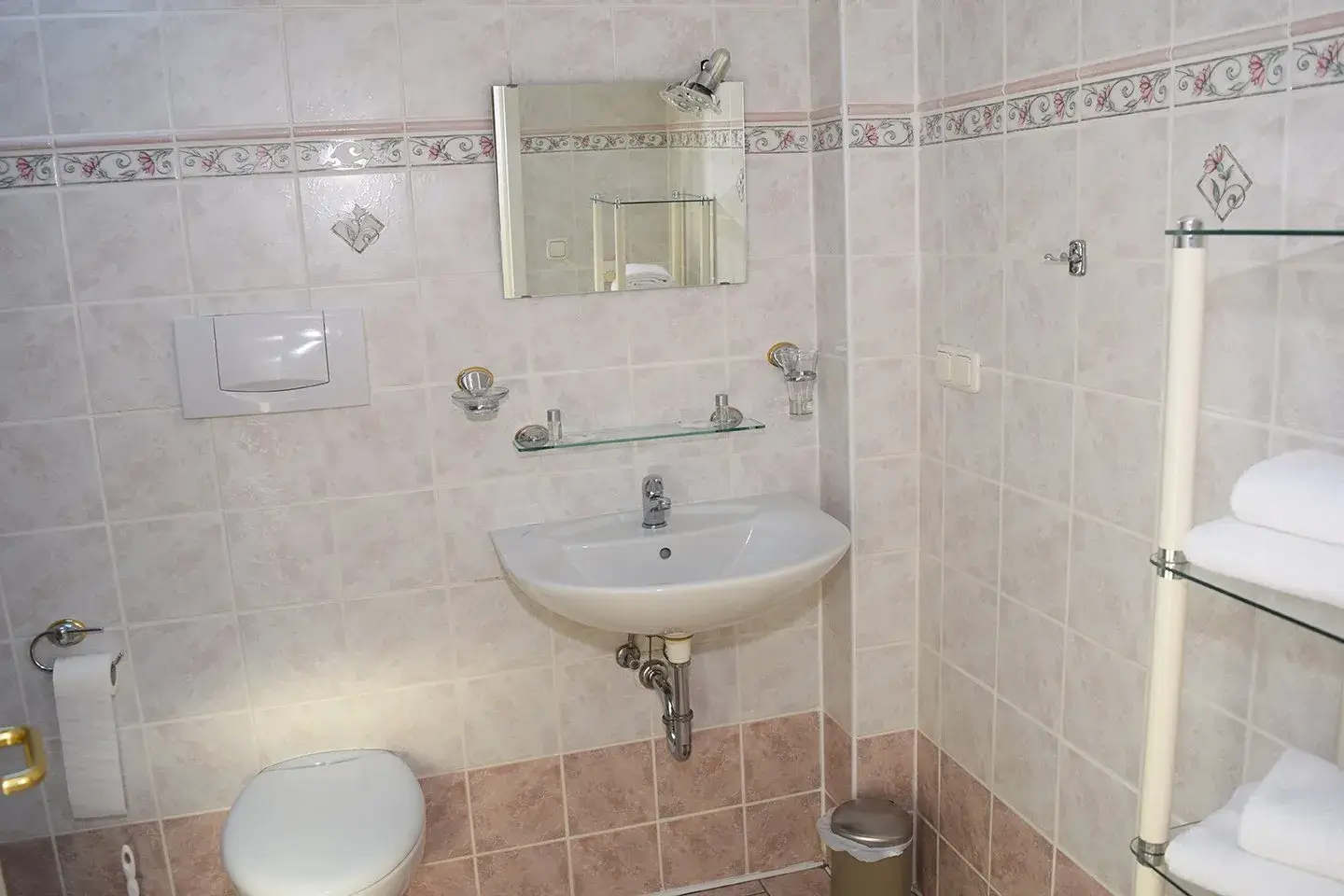 gefliestes Badezimmer mit WC und Waschbecken mit Spiegel