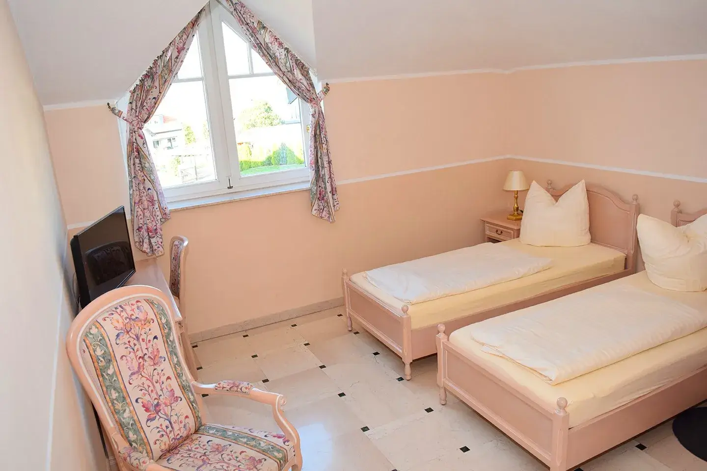 Blick in ein Zimmer mit 2 Einzelbetten, Stuhl und Fenster