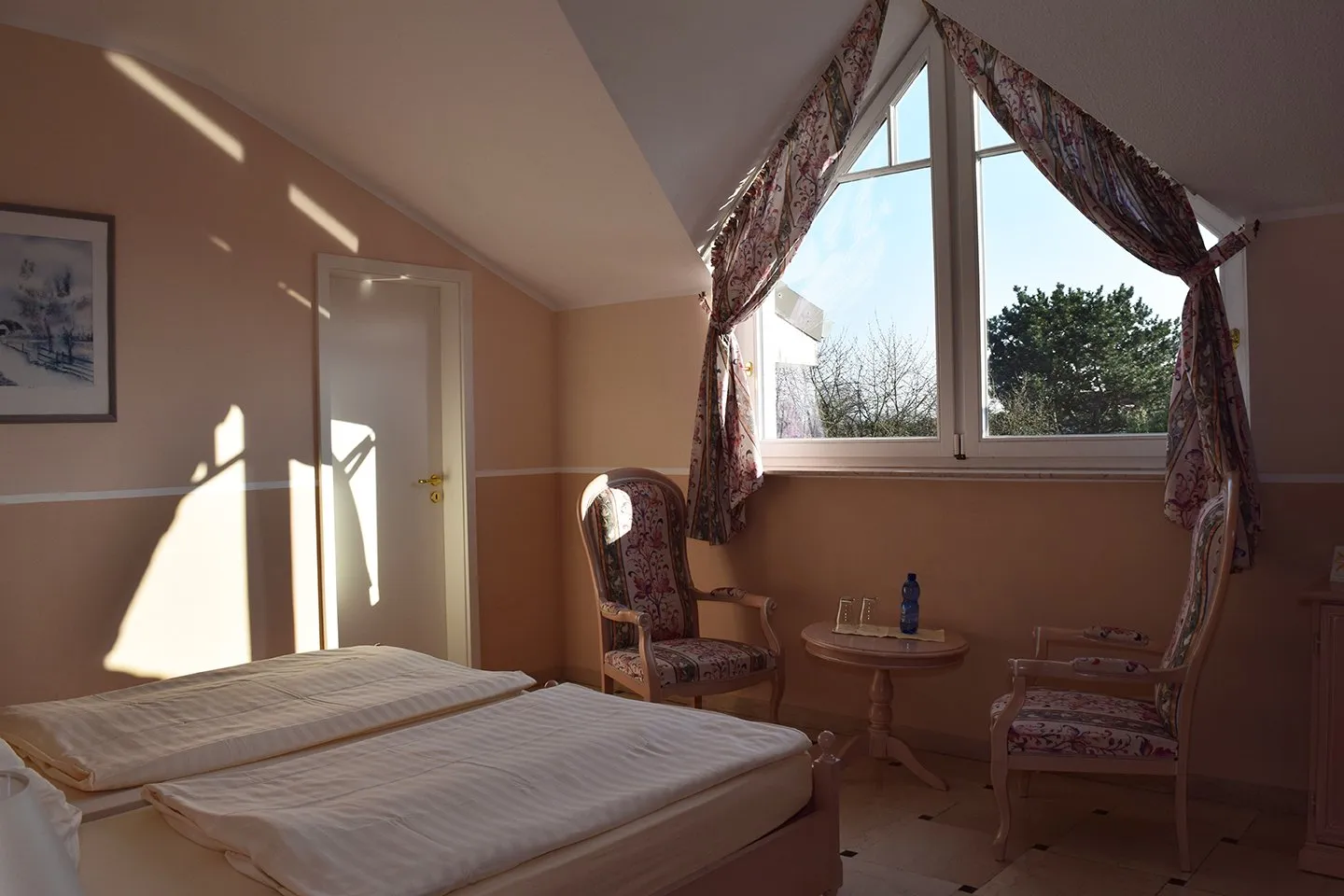 Doppelbett mit Tisch und 2 Stühlen im Gästezimmer im italienischen Stil mit Blick auf das Fenster