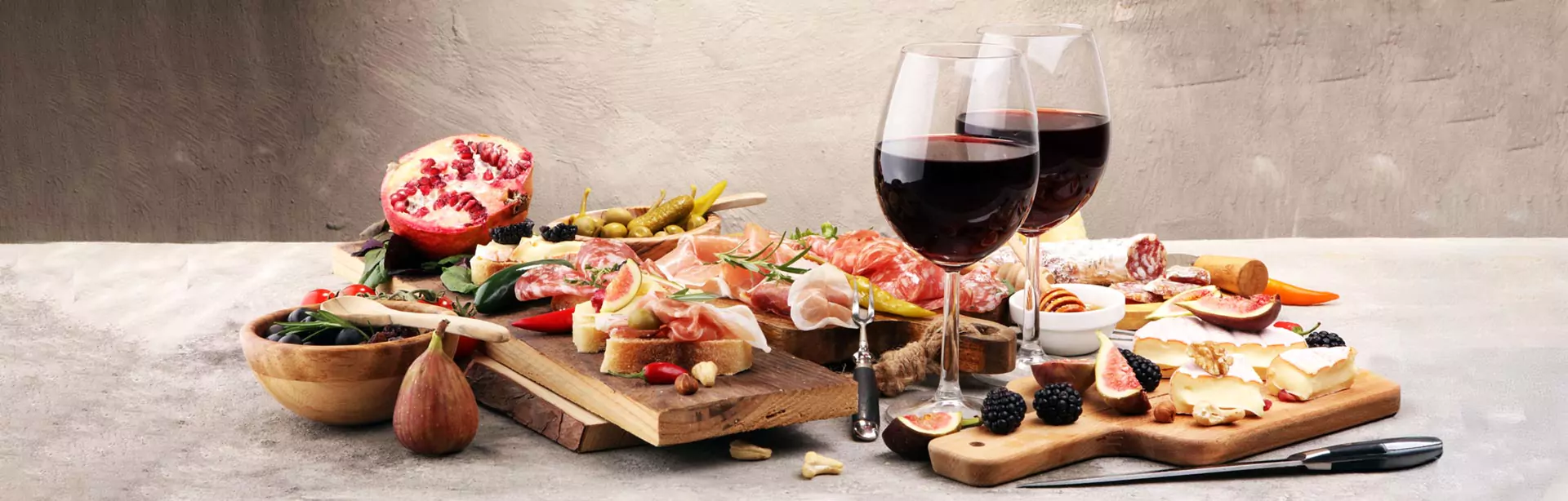 Italienische Antipasti mit Wein, Snacks, verschiedenen Käsesorten, Oliven, saure Gurken, Prosciutto di Parma, Salami, Feigen, Brombeeren und Granatapfel