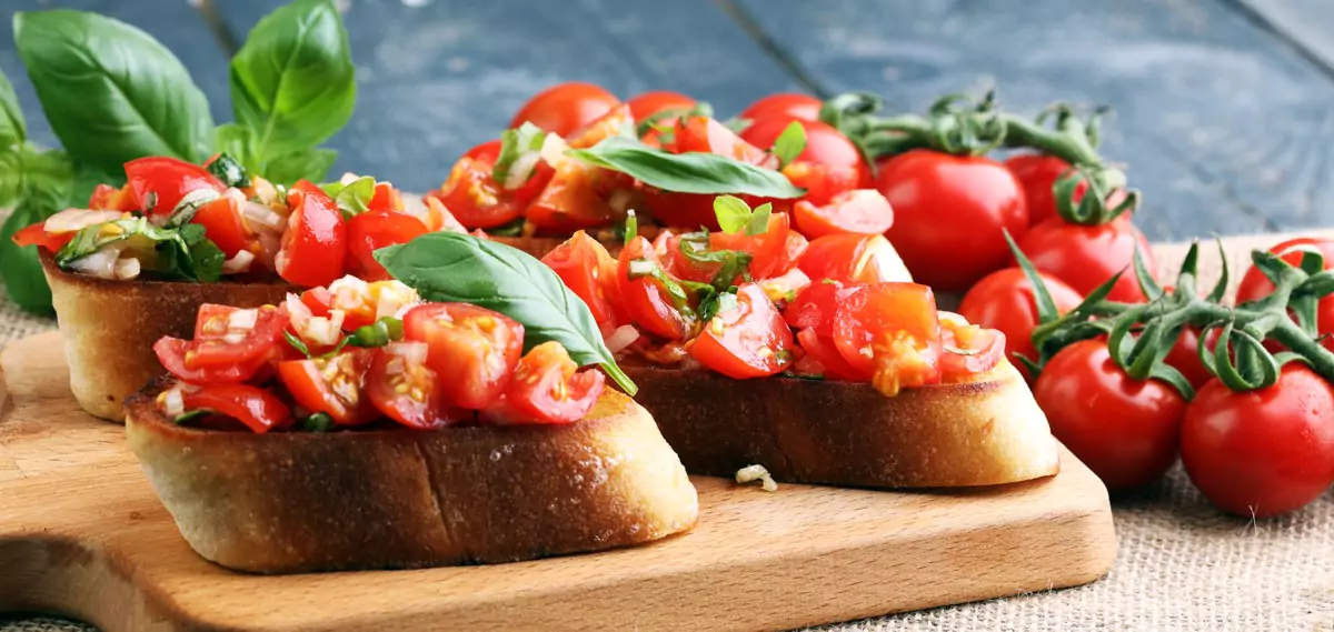 Bruschetta von geröstetem Baguette, mit Tomatenstückchen und mit Basilikum garniert