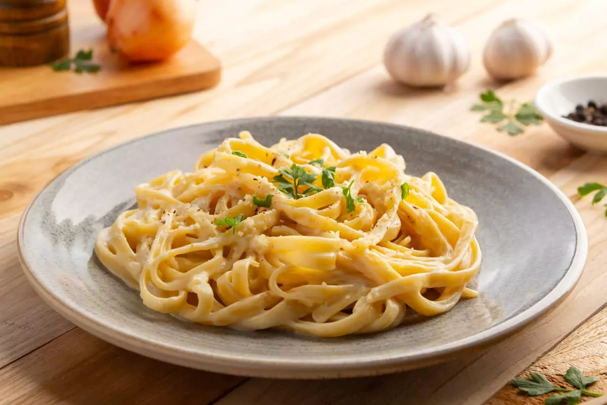 Cremige Fettuccine-Nudeln mit Carbonara-Sauce, garniert mit Petersilie und Parmesankäse auf einem Teller.