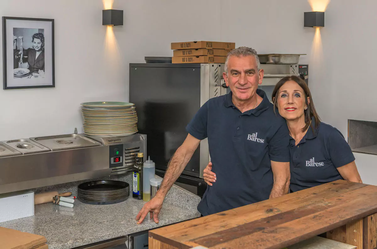 2 glückliche Menschen stehen in der Küche eines RFestaurants und lächeln