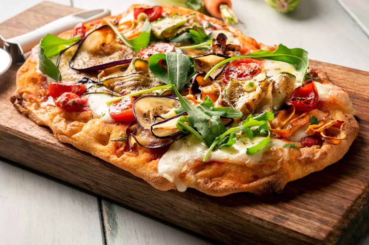 vegetarische Pinsa mit gegrilltem Gemüse und Burrata mit Rucolablättern garniert