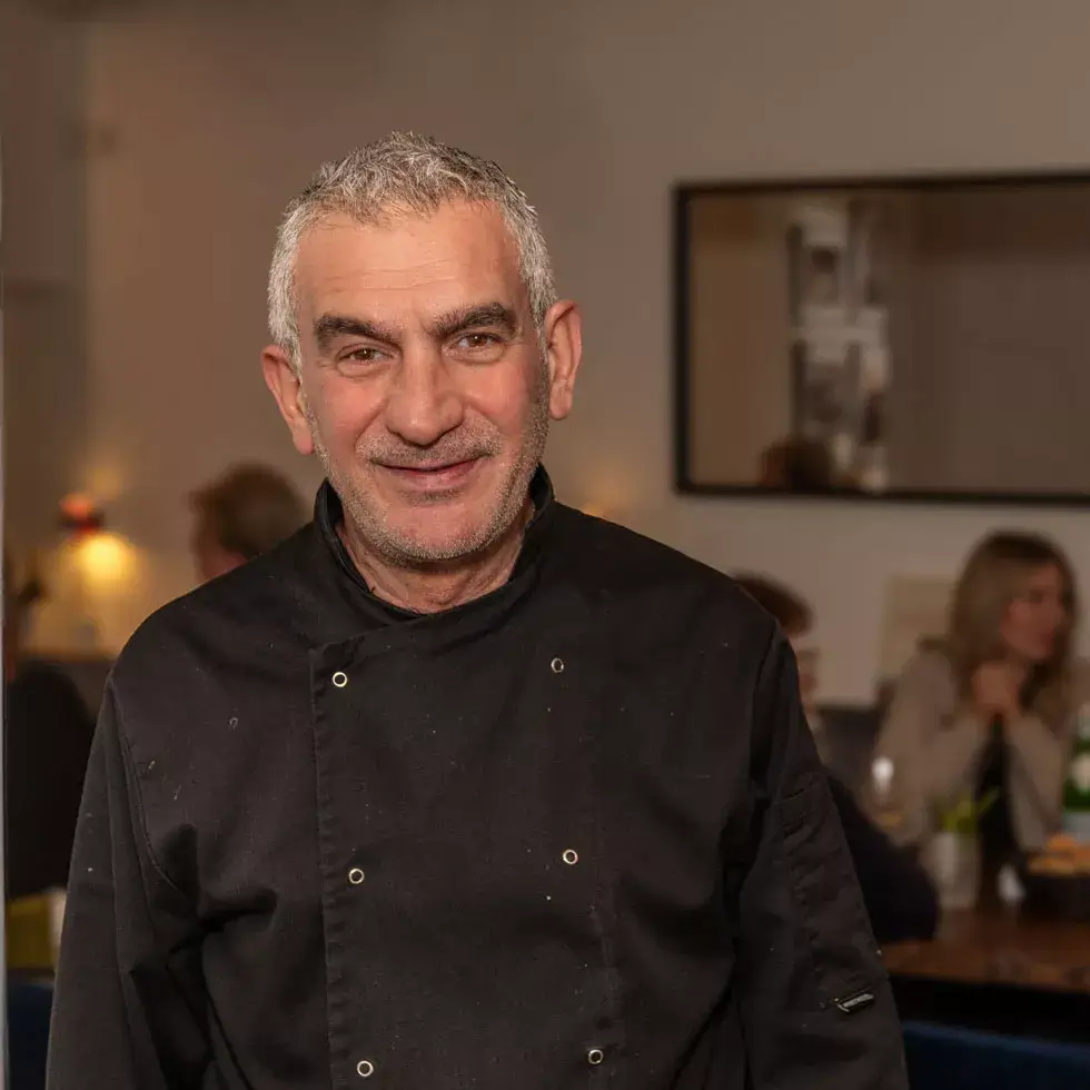 älterer Herr mit schwarzem Kellneroberteil lächelt